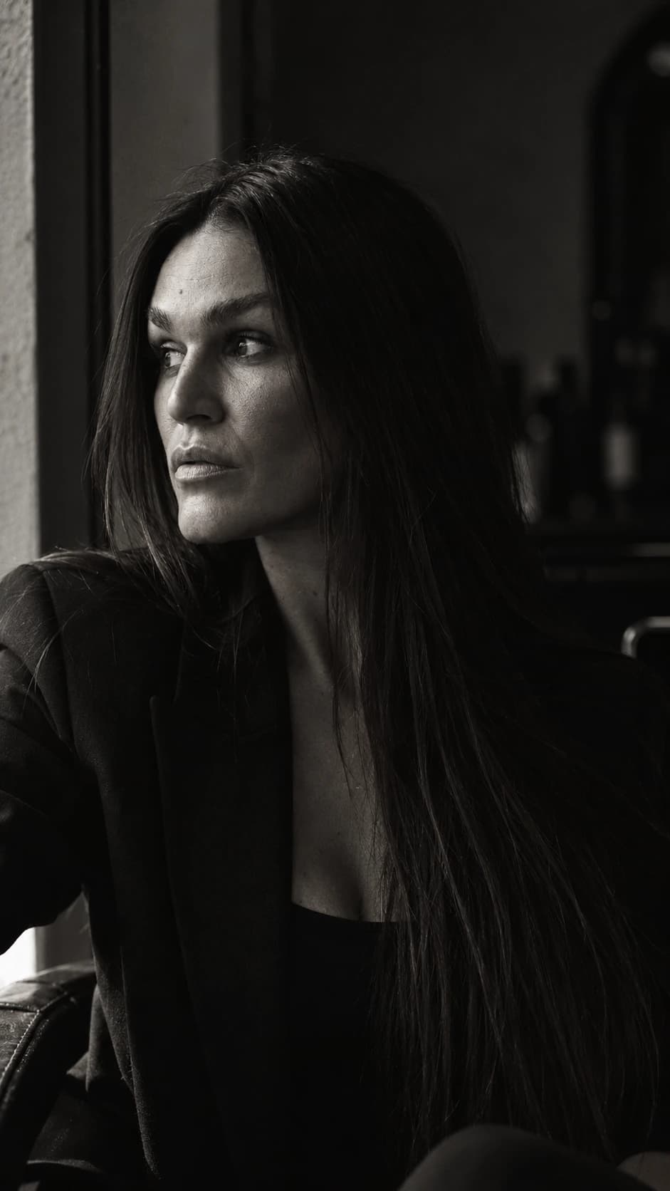 Black-and-white AI portrait of Sandra beside a window.